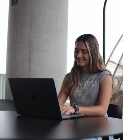 Young woman using a laptop in a modern indoor setting, focused on online study.